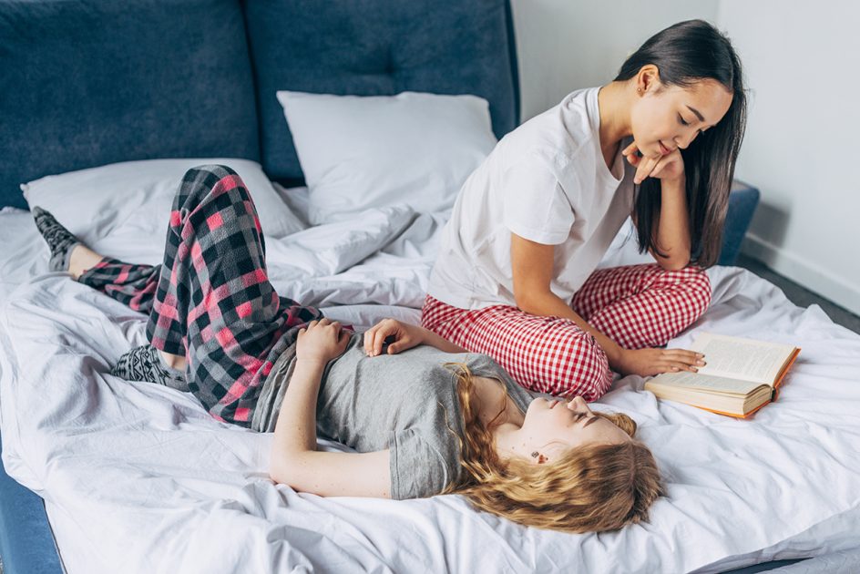 Kaksi henkilöä makoilee pyjamissa sängyllä.